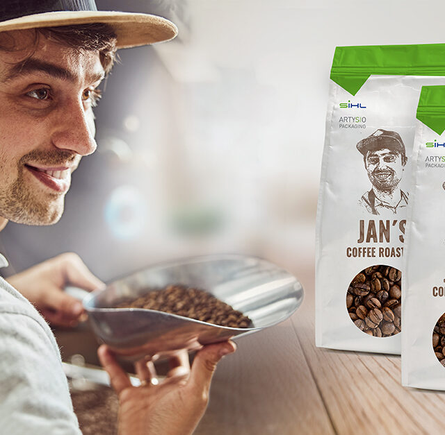 Mann hält Schaufel mit Kaffeebohnen, daneben zwei Kaffeebohnen-Verpackungen mit seinem Foto