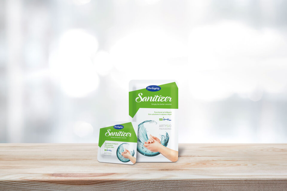 Großes und kleines Desinfektionsmittel Sachet auf Holzplatte vor grauem Hintergrund